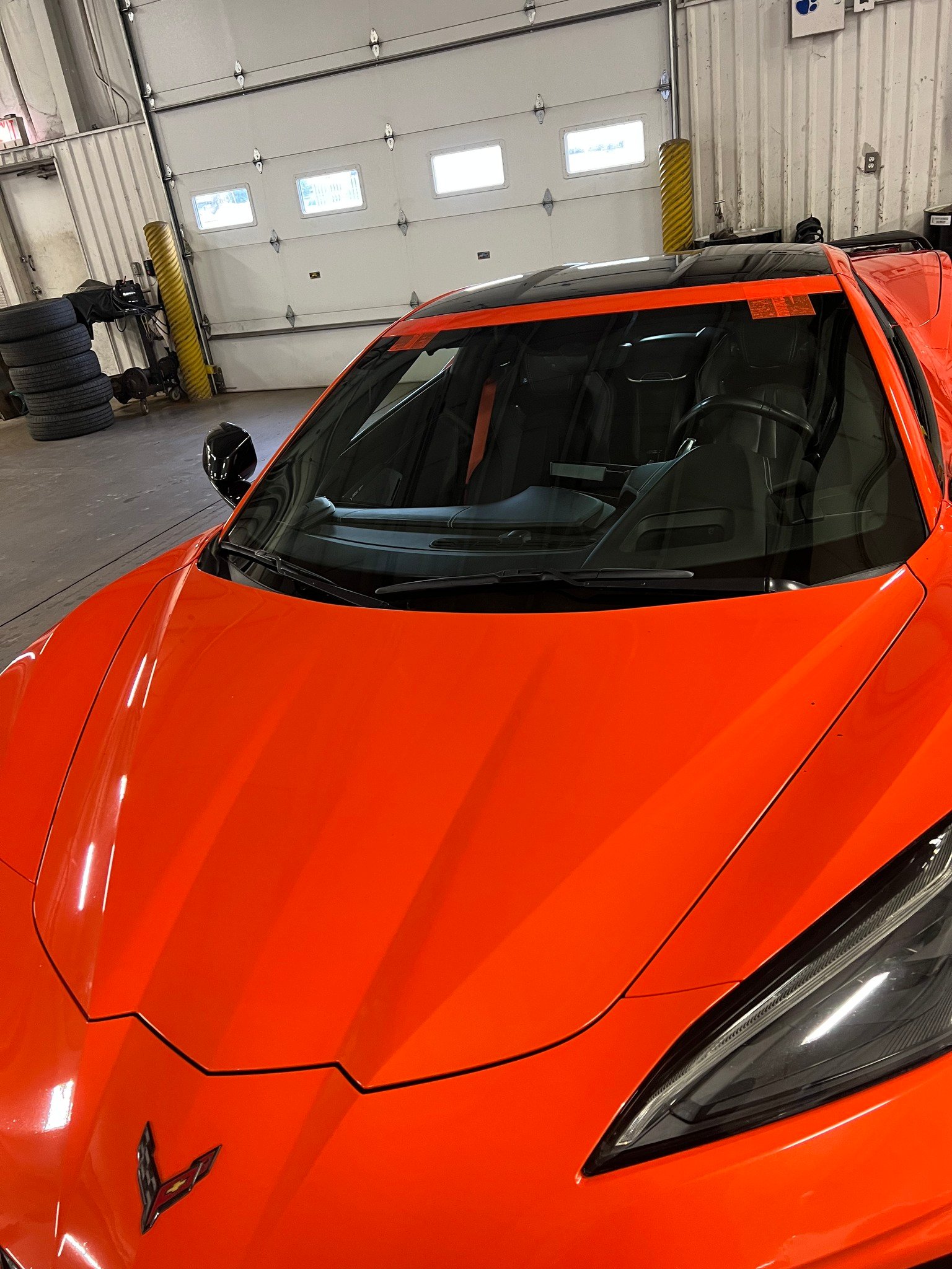 Completed windshield replacement on an orange Corvette C8 in the B-Rite shop
